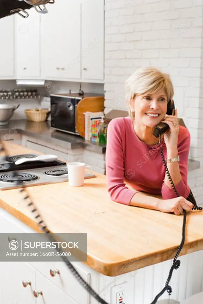 Mature woman talking on telephone in kitchen