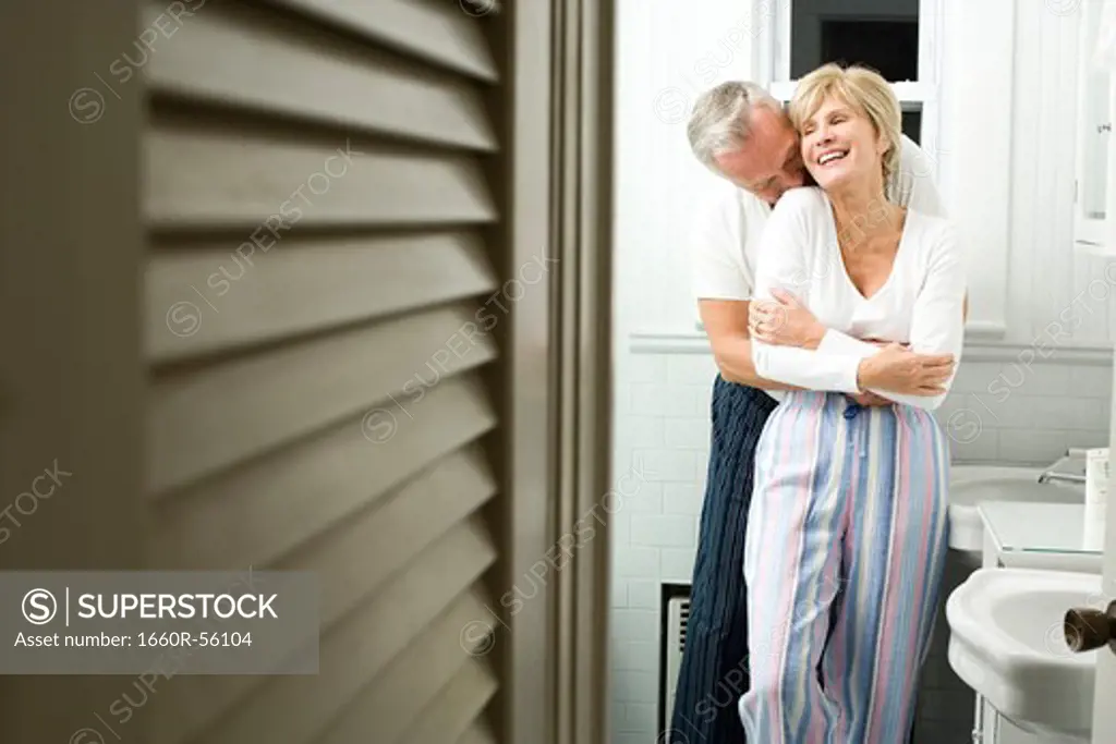 Mature couple in bathroom embracing