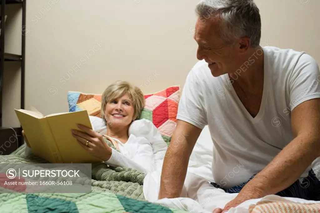 Woman in bed reading with mature man