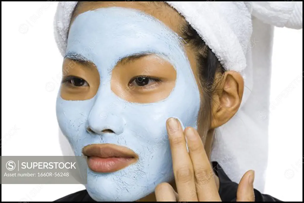 Closeup of woman applying facial mask with hair towel