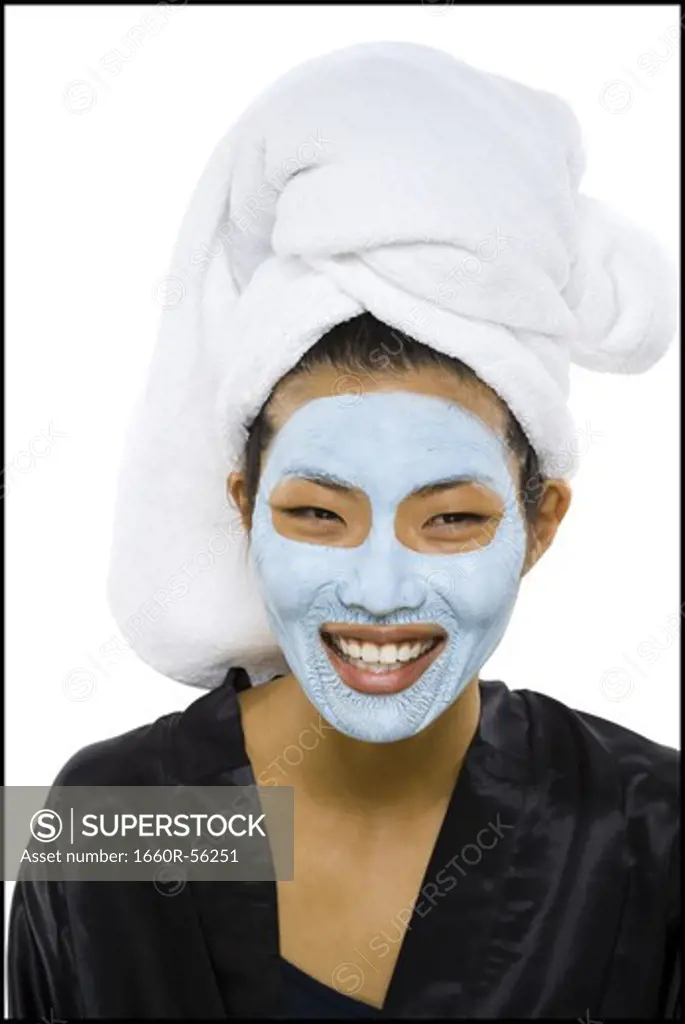 Closeup of woman smiling with facial mask and hair towel
