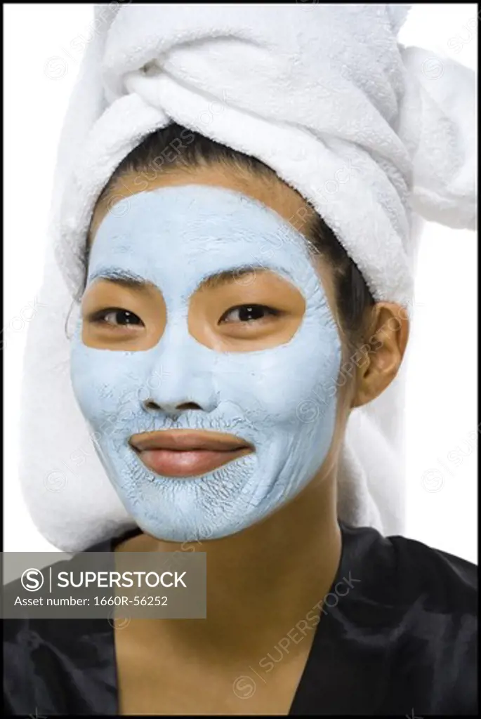 Closeup of woman smiling with facial mask and hair towel