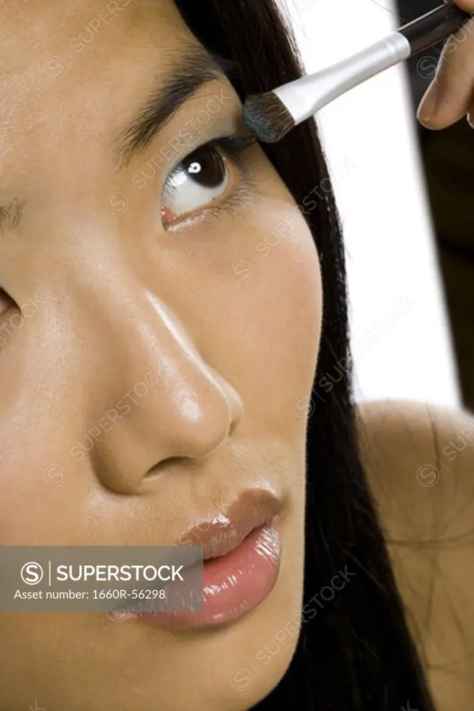 Closeup of woman applying eyeshadow with makeup brush