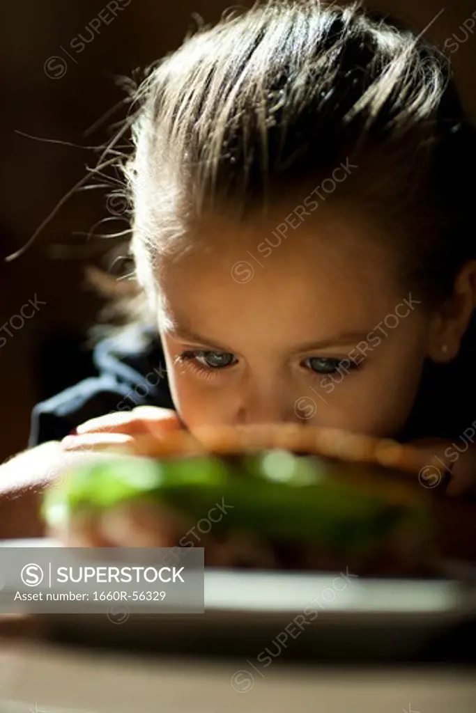 Young girl looking at sandwich sulking