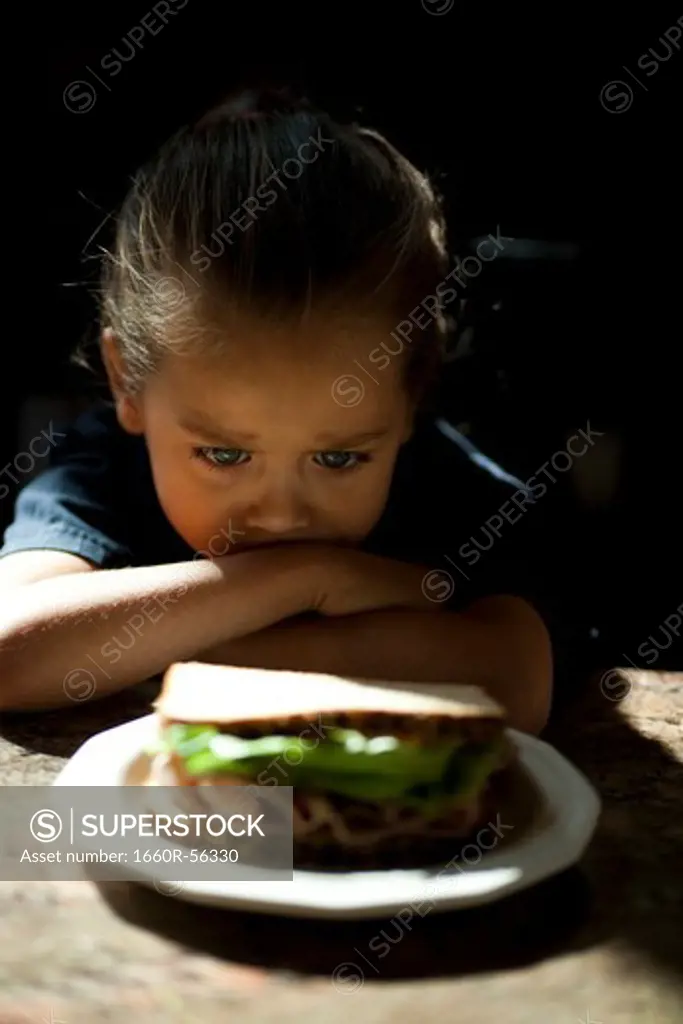 Young girl looking at sandwich sulking
