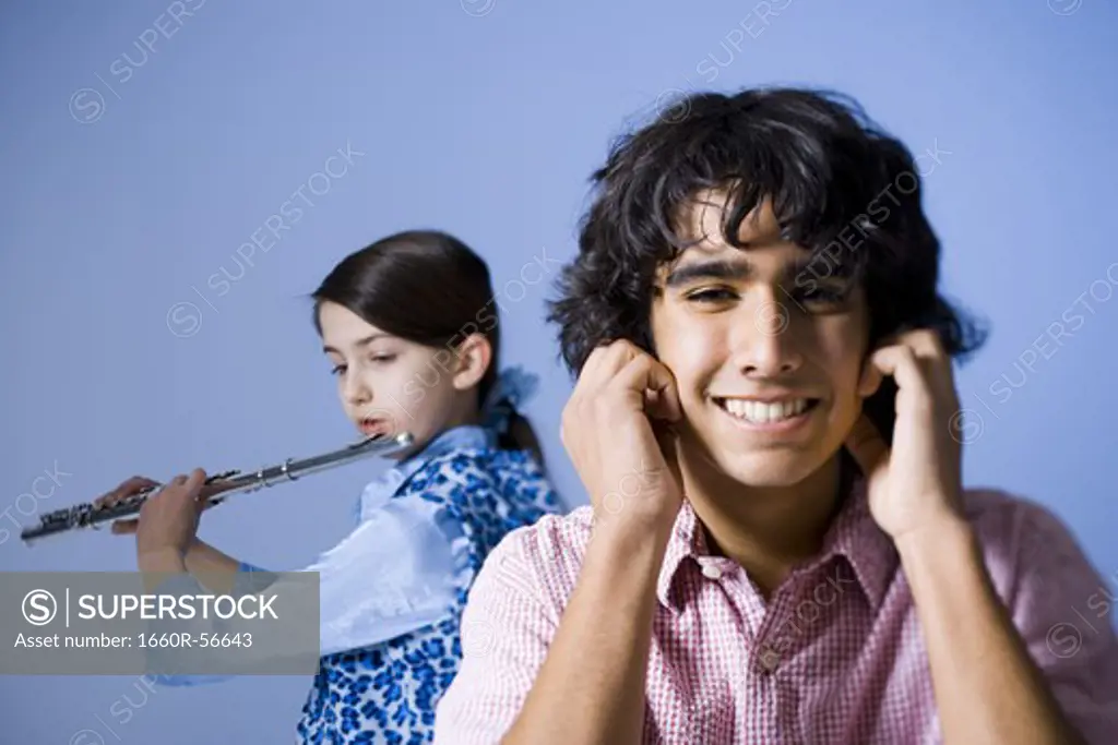 Girl playing the flute with her brother not listening