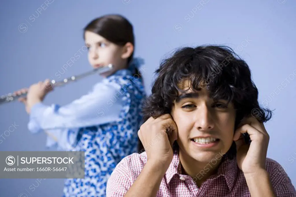 Girl playing the flute with her brother not listening
