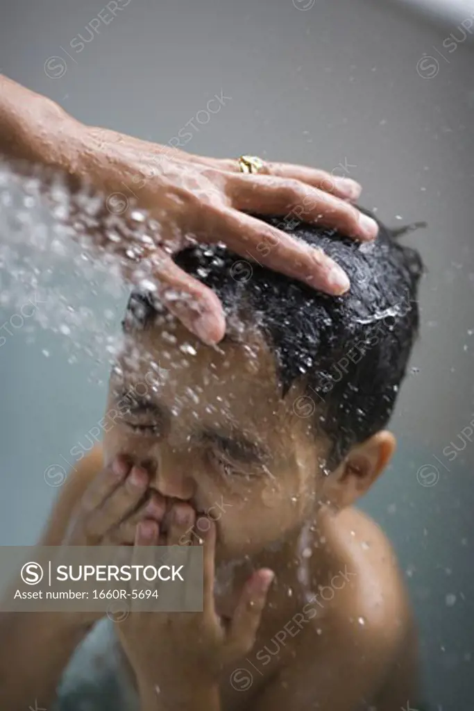 Mother washing son in bathtub