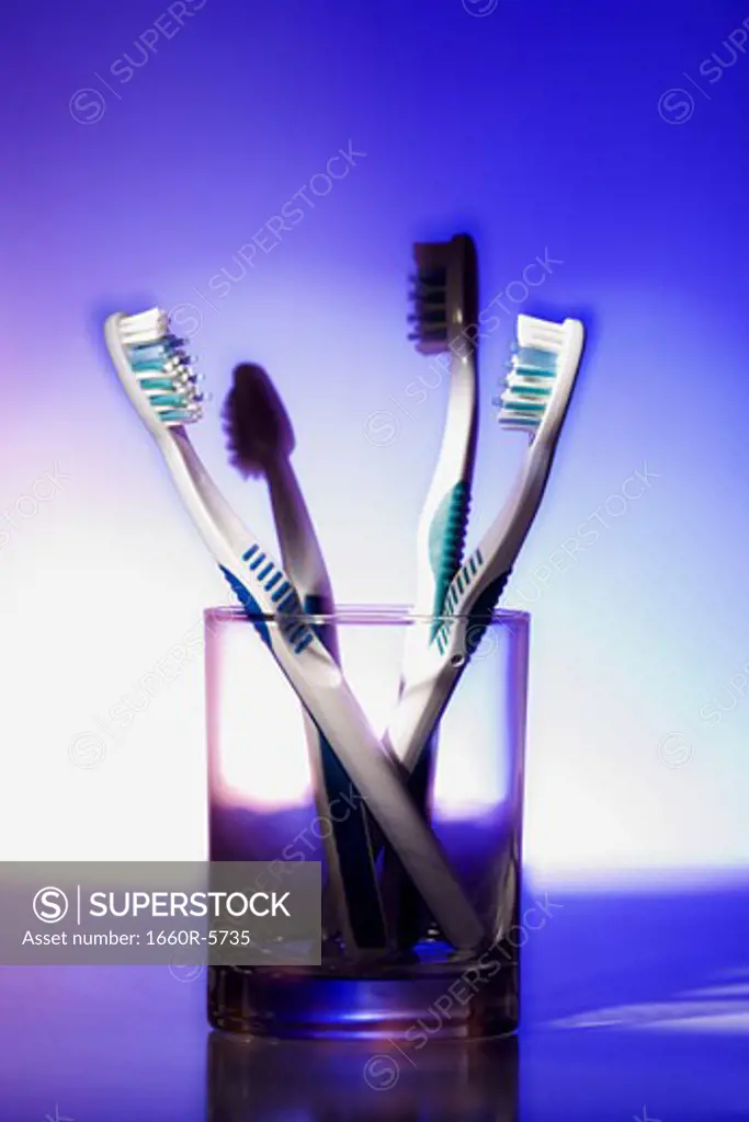 Close-up of four toothbrushes in a glass