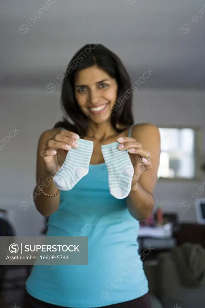 Portrait of a pregnant woman holding baby socks