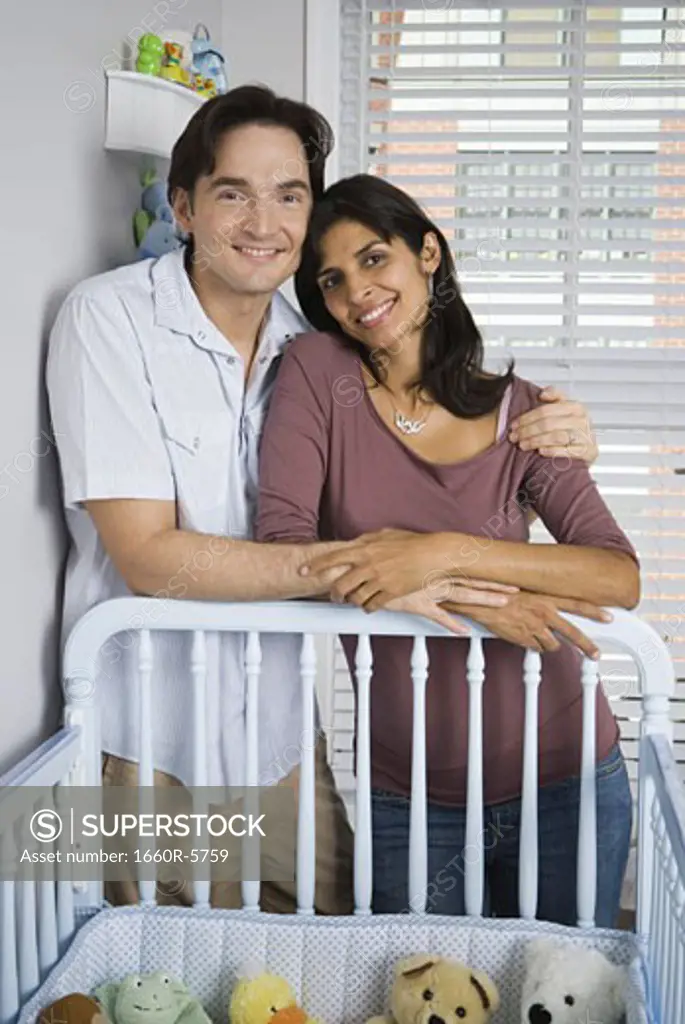 Portrait of a couple leaning on a crib