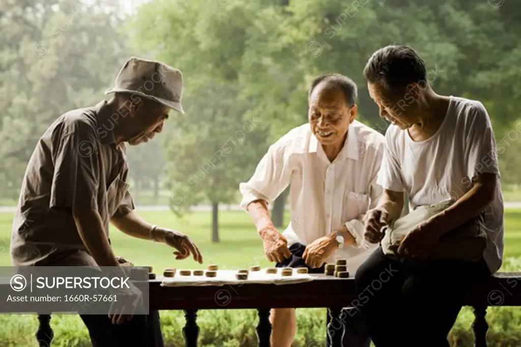 Three men playing board game outdoors smiling