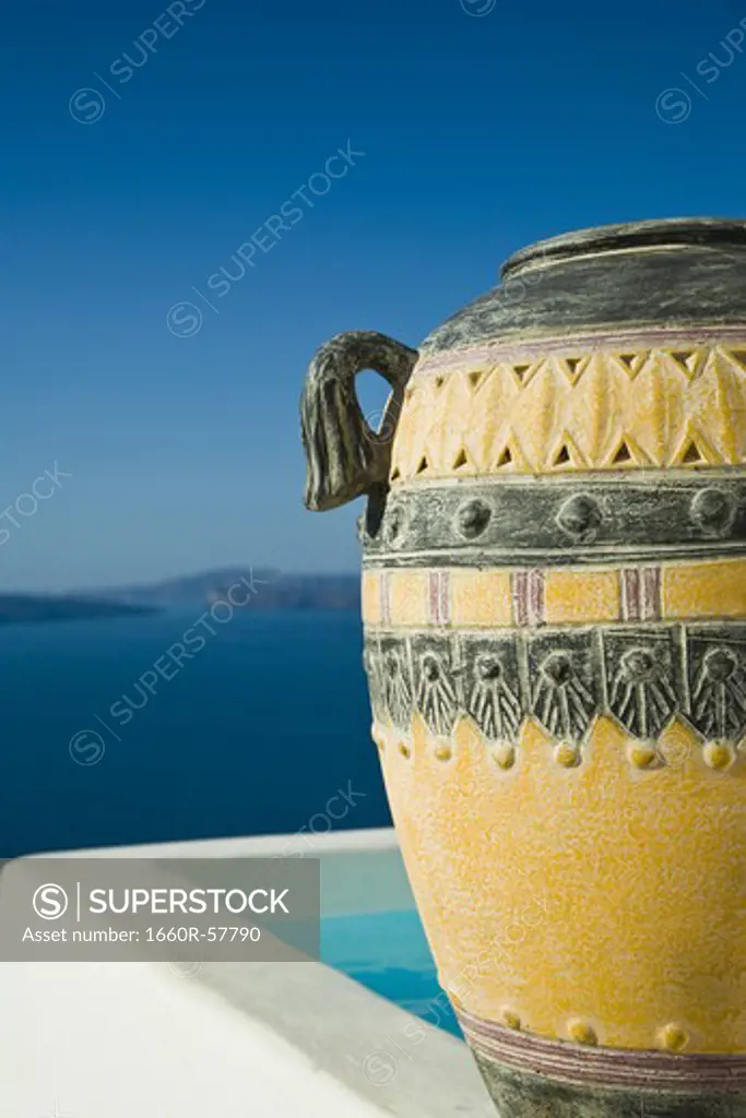 Closeup of urn with infinity pool with mountains and water in background