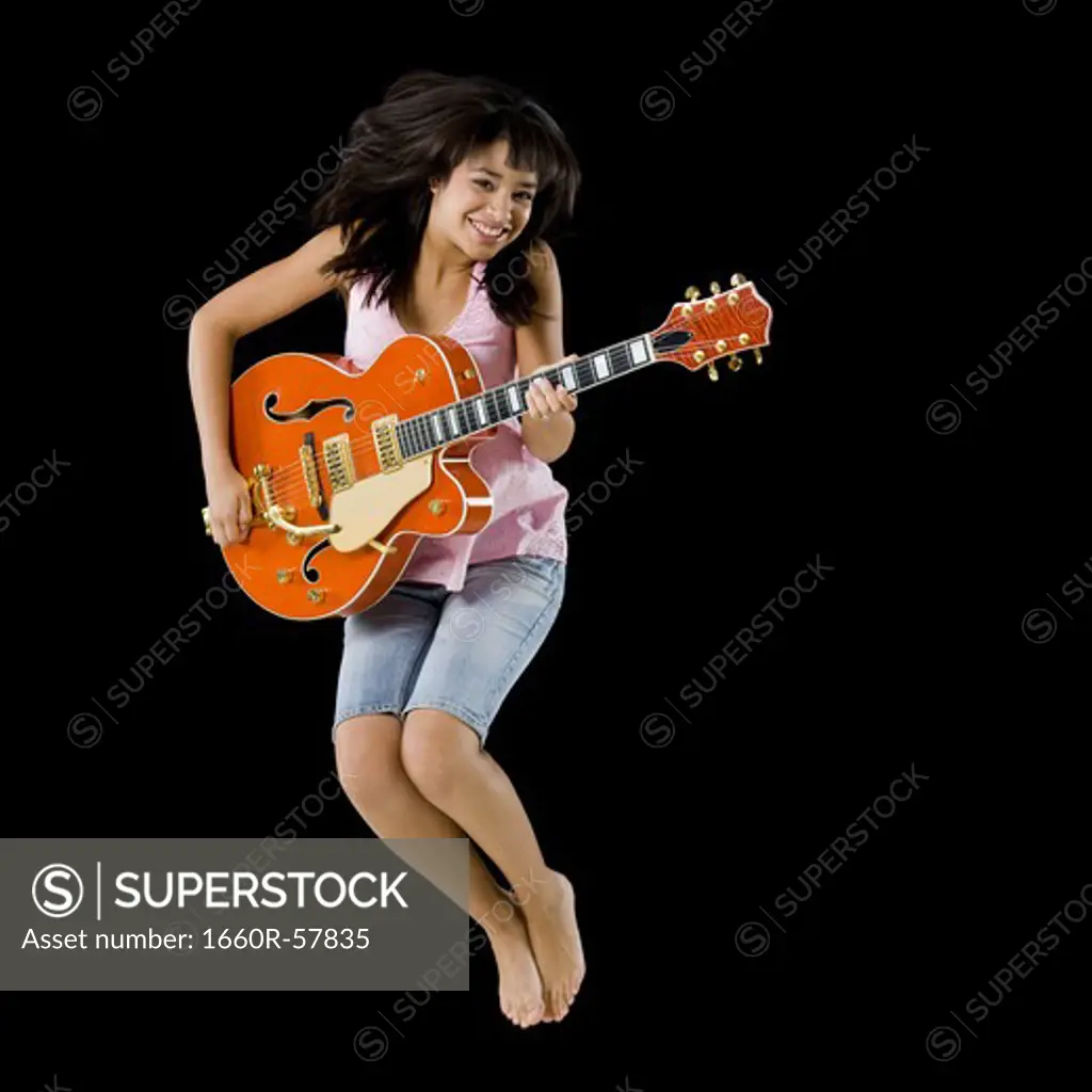 Woman with guitar leaping and smiling