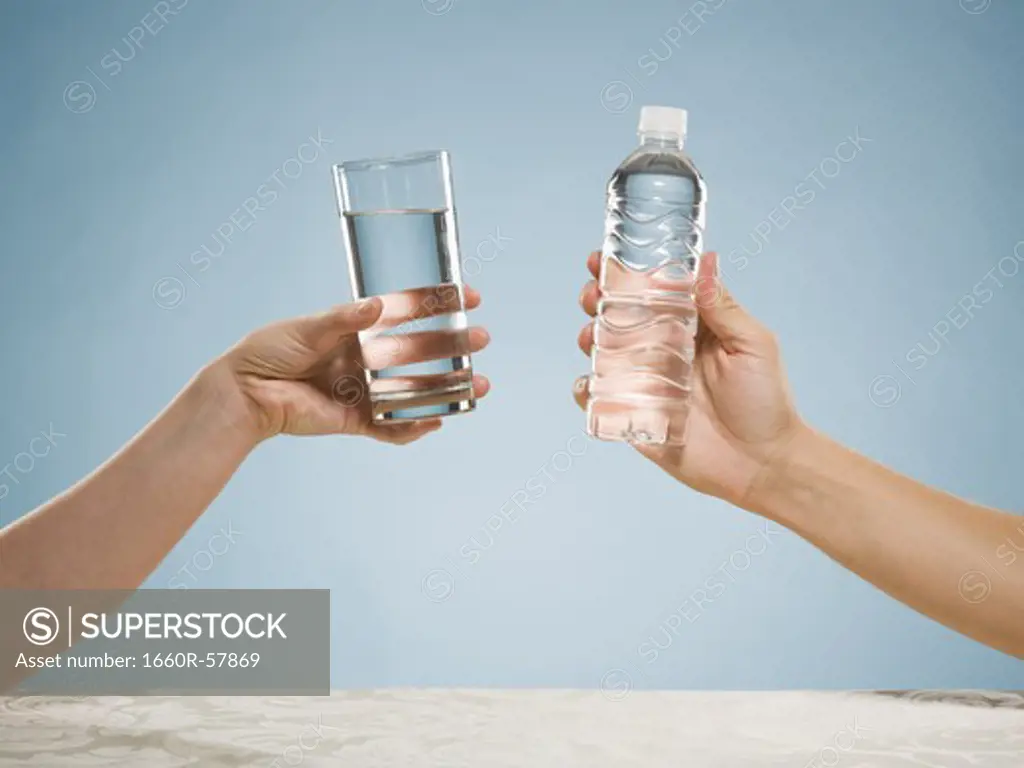 Hand holding glass of water and hand holding bottled water