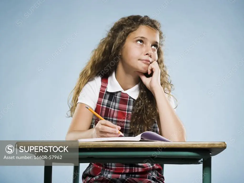 Girl sitting at desk with workbook looking bored