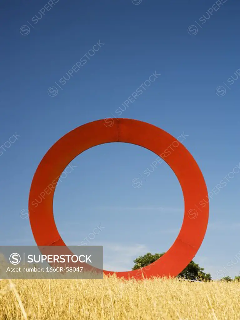 Giant red O in field with blue sky