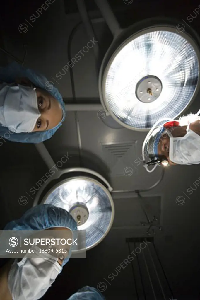 Low-angle view of three surgeons standing over an operating table