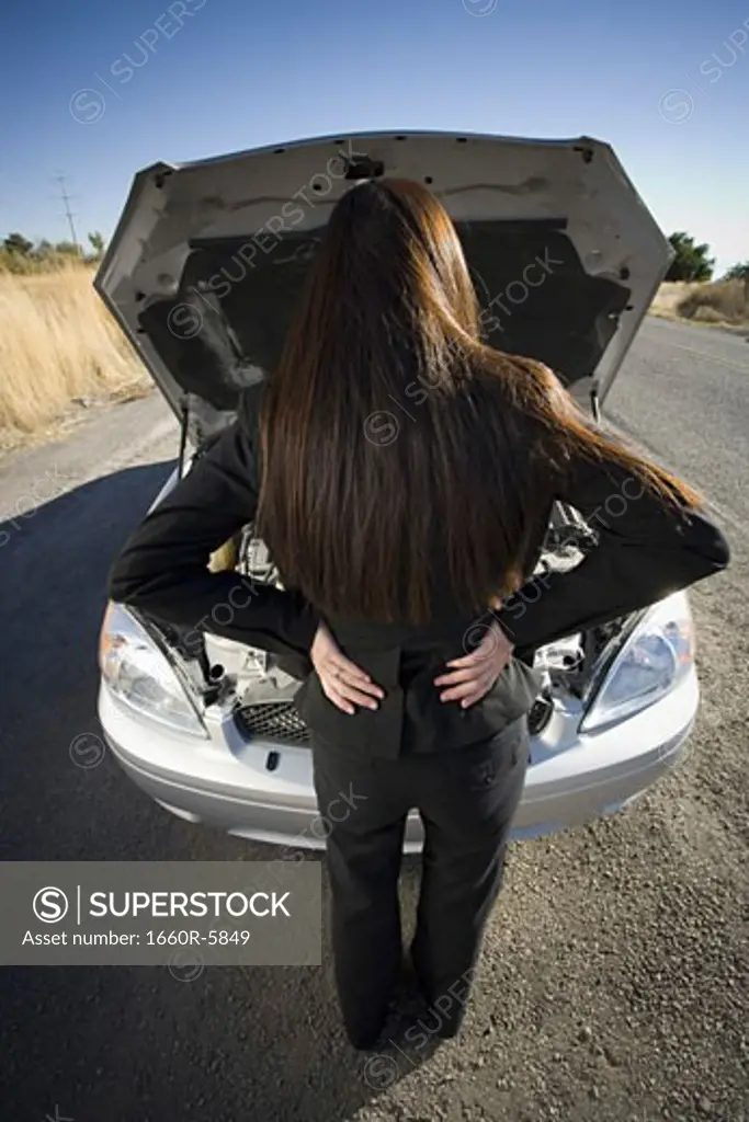Rear view of a woman checking her car engine