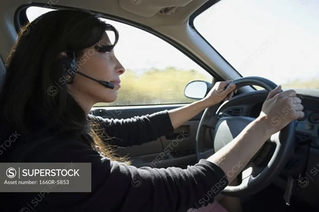 Profile of a woman driving a car and wearing a headset