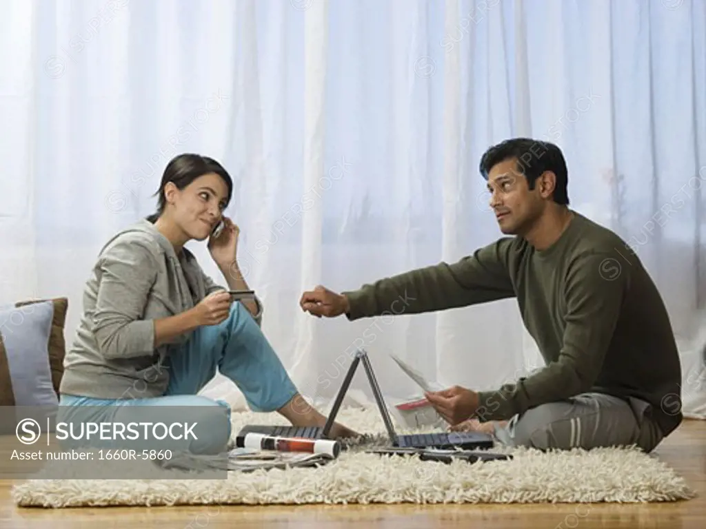 Profile of a man and a woman sitting on the floor with laptops