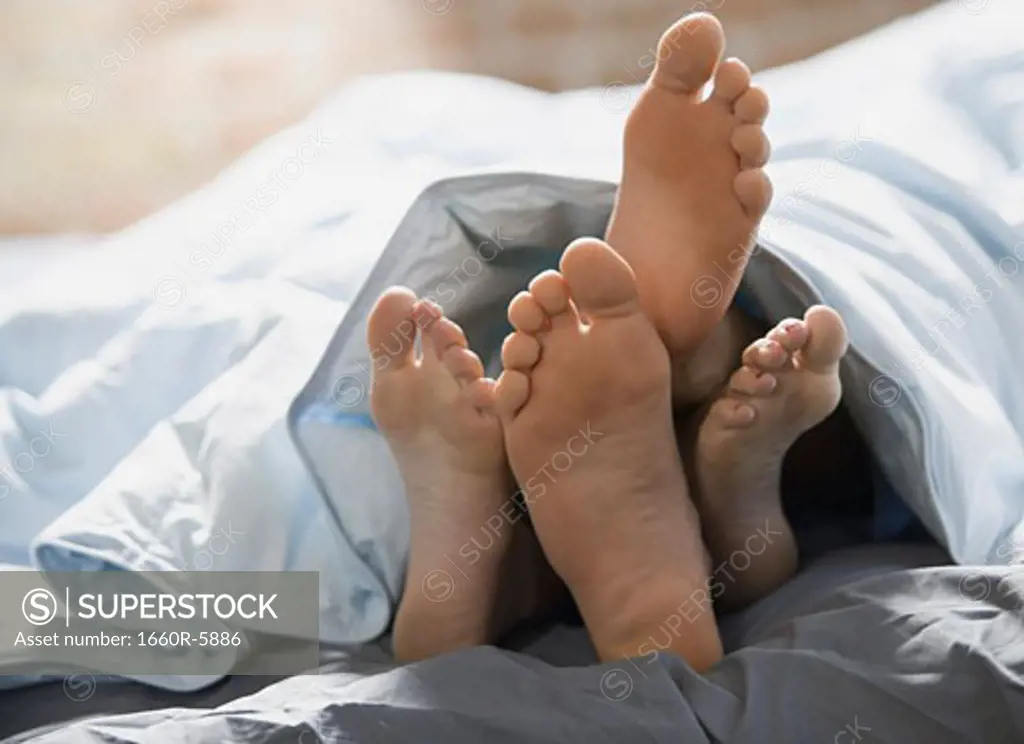 Feet of a couple lying on the bed