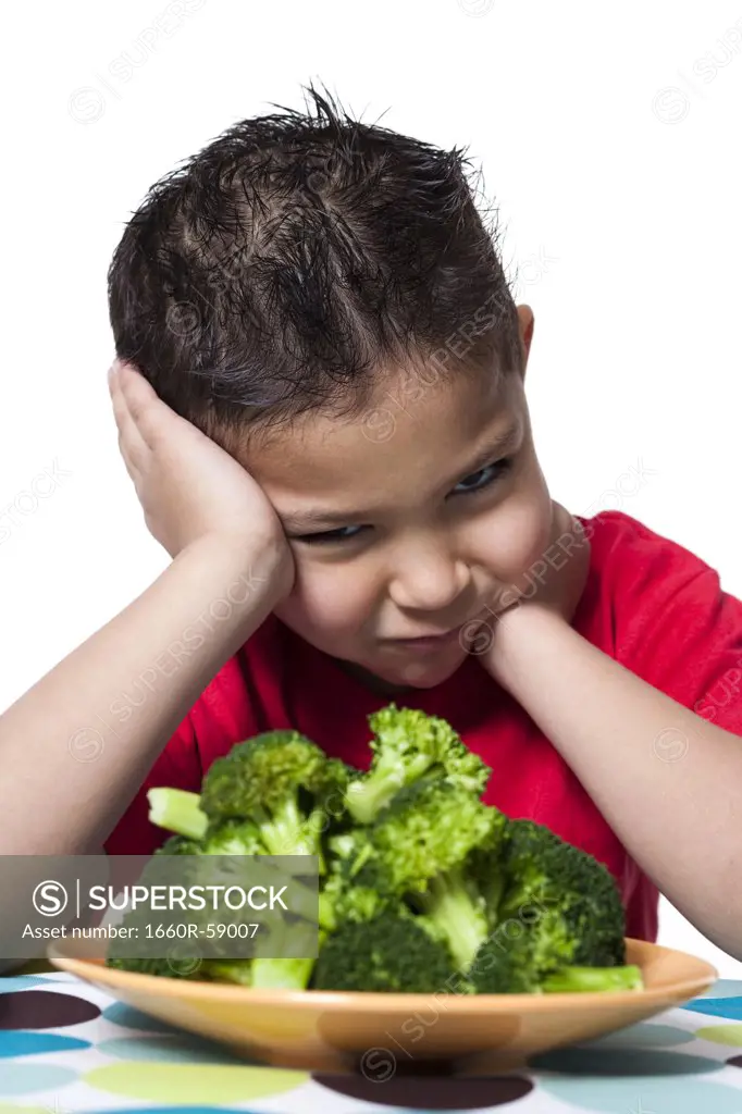 Boy with plate of broccoli frowning