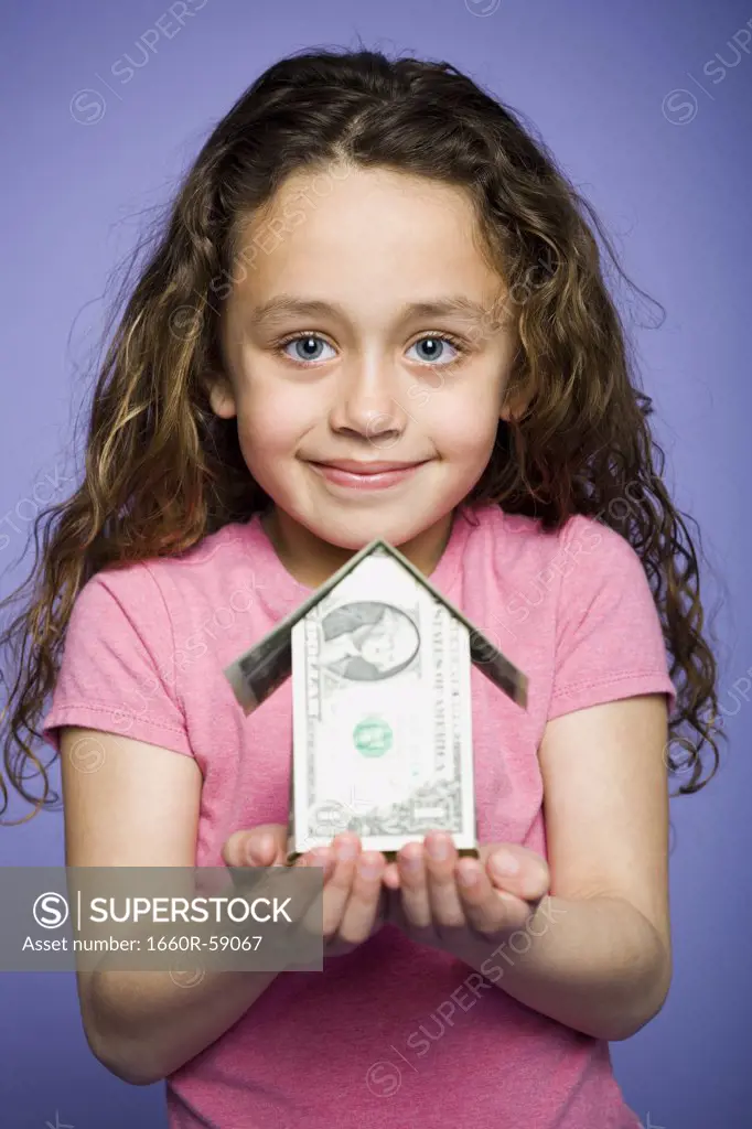 Young girl with a little house made of banknotes
