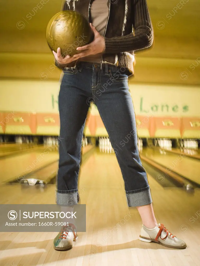 Low section view of a teenage girl standing at a bowling alley