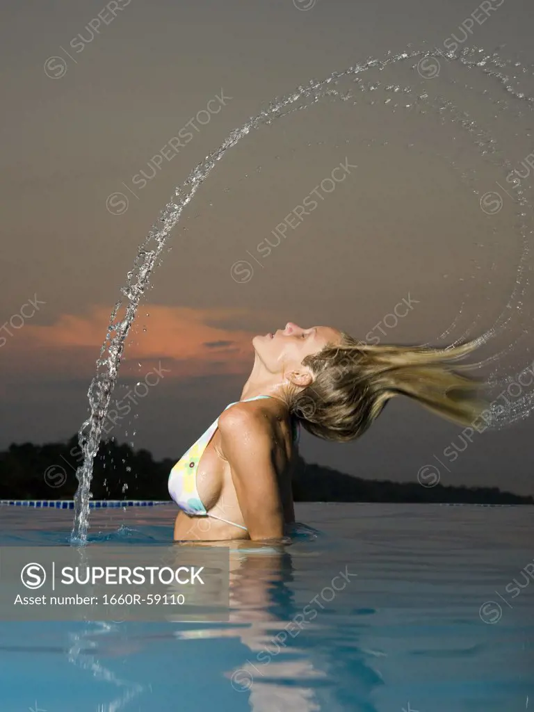 Profile of a young woman throwing back her hair in a swimming pool