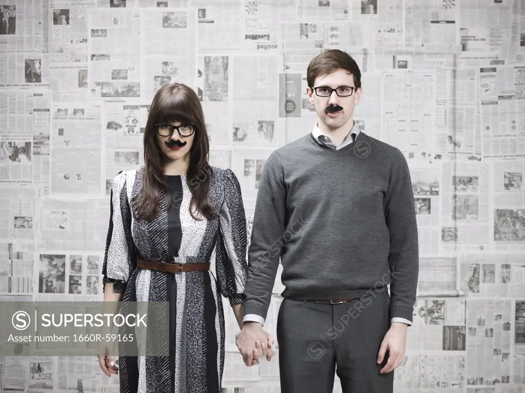 Studio portrait of young couple wearing fake moustaches