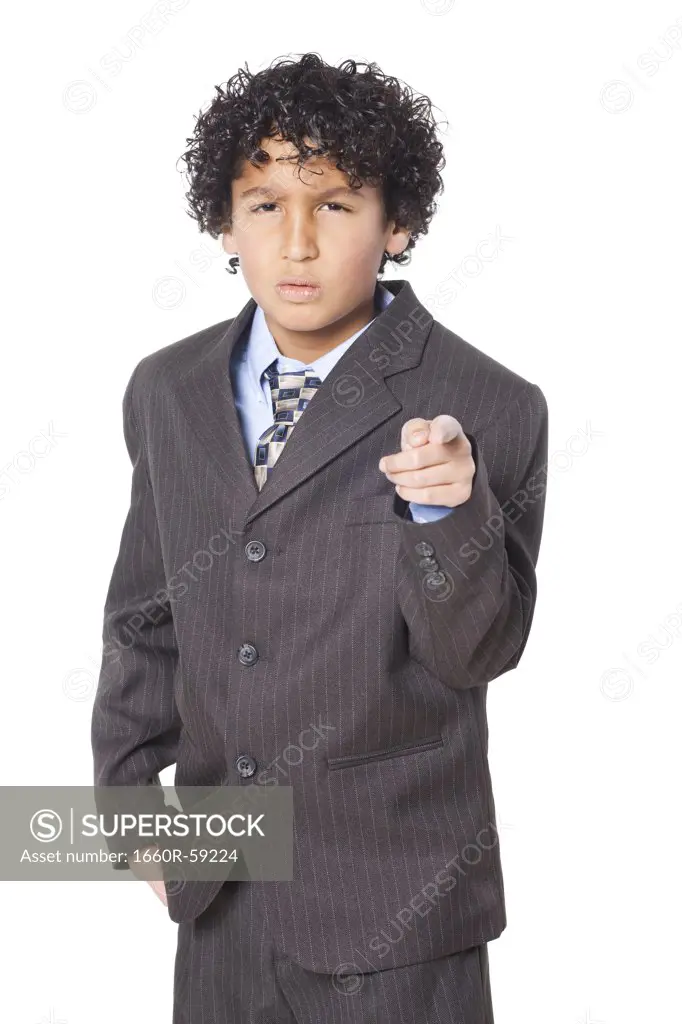 Studio portrait of boy (8-9) wearing suit, pointing