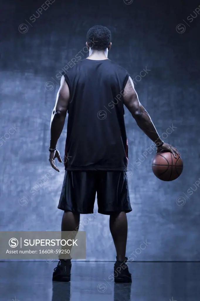 Male basketball player holding ball, studio shot