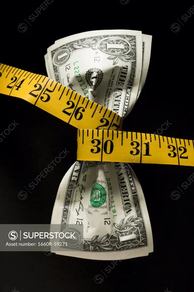 One dollar banknotes tied up with measuring tape against black background