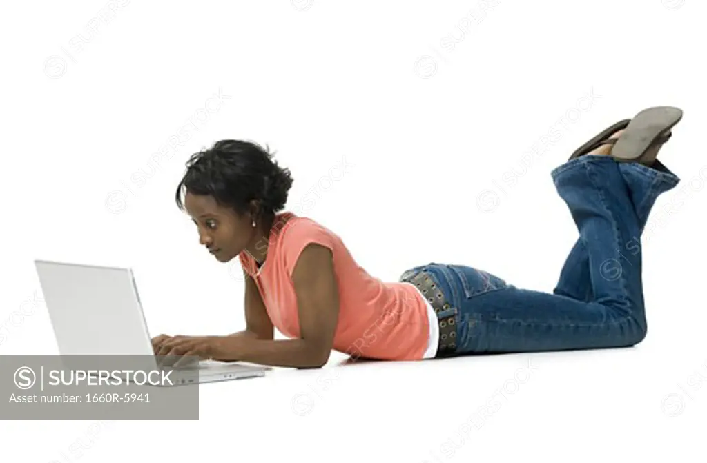 Profile of a young woman lying on the floor using a laptop