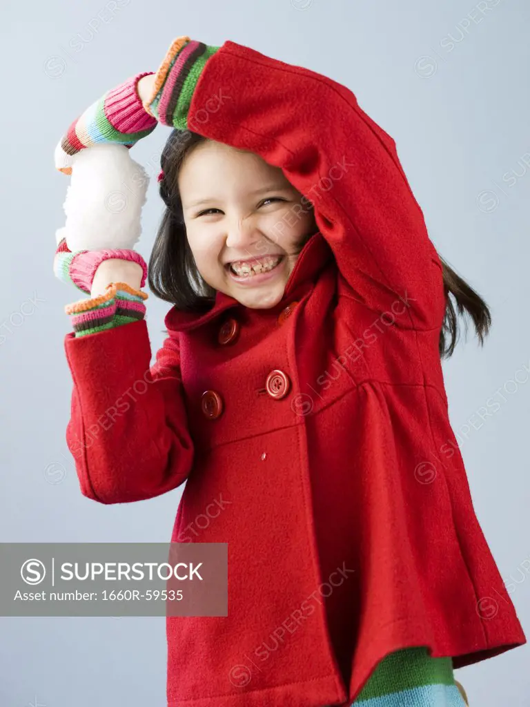 Girl (6-7) in red coat holding snow ball