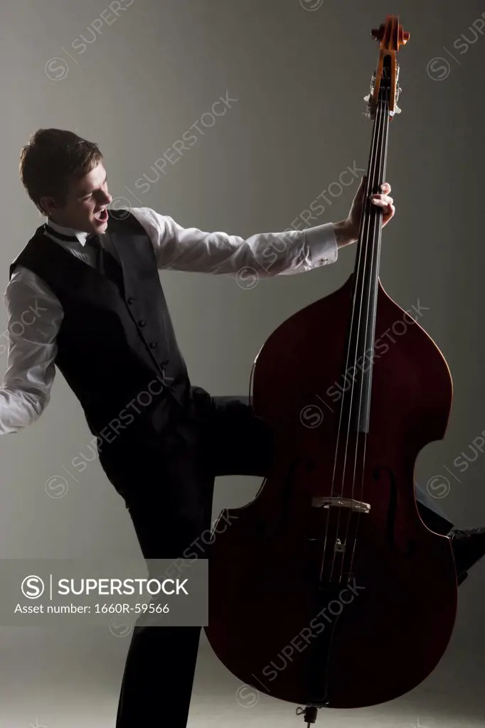 Young man playing double bass, studio shot