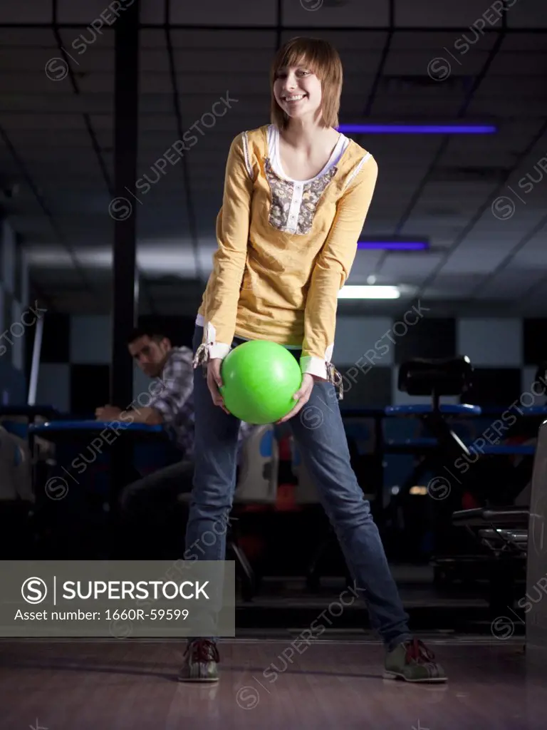USA, Utah, American Fork, young woman holding bowling ball and smiling