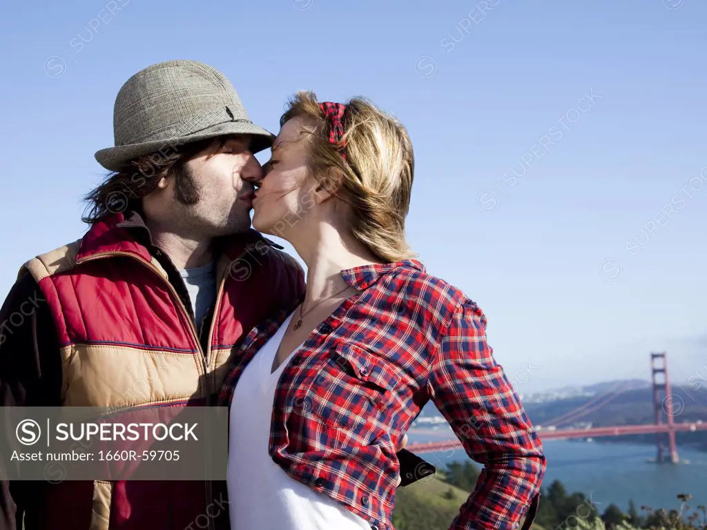USA, California, San Francisco, young couple kissing, Golden Gate Bridge in background
