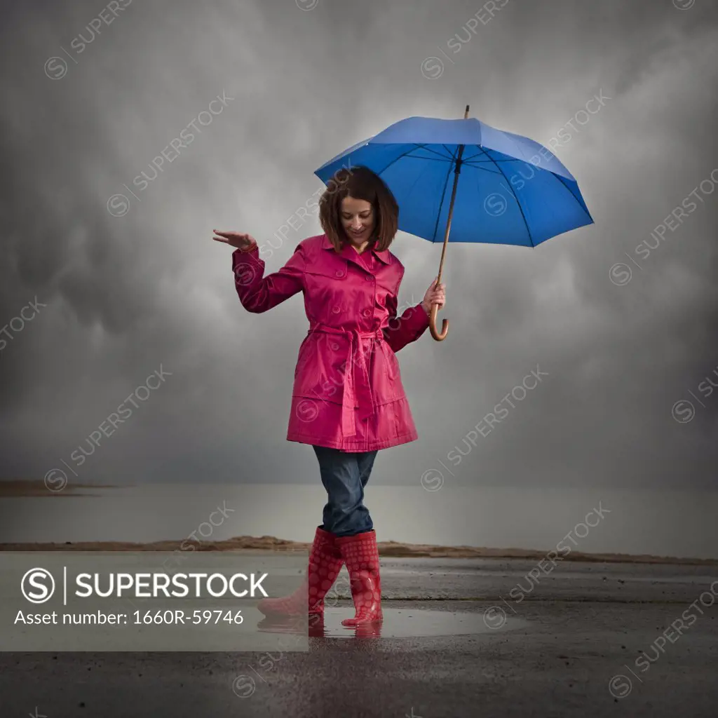 USA, Utah, Orem, woman with umbrella standing in puddle