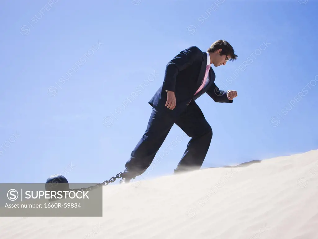 USA, Utah, Little Sahara, businessman wearing ball and chain in desert