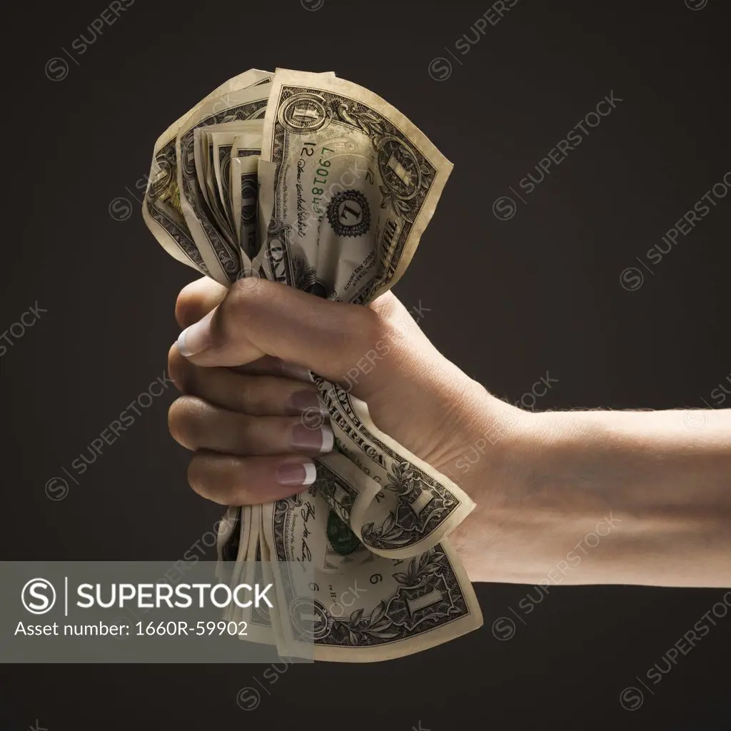 Young woman's hand holding a wad of US one dollar bills