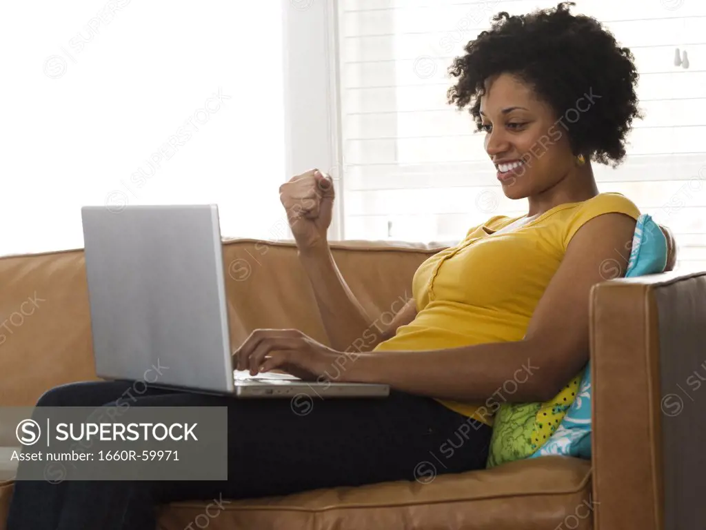 USA, Utah, Provo, young woman sitting on sofa and using laptop