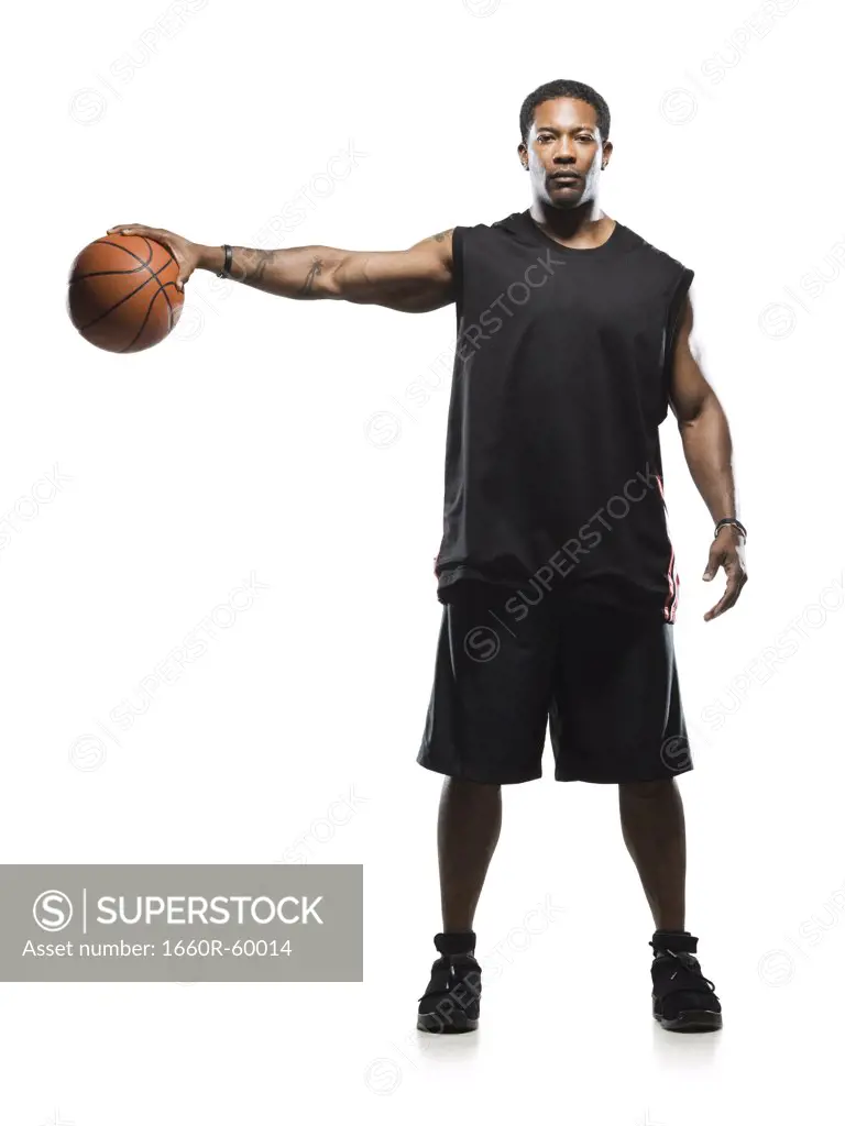 Mid adult man holding basketball in air, portrait