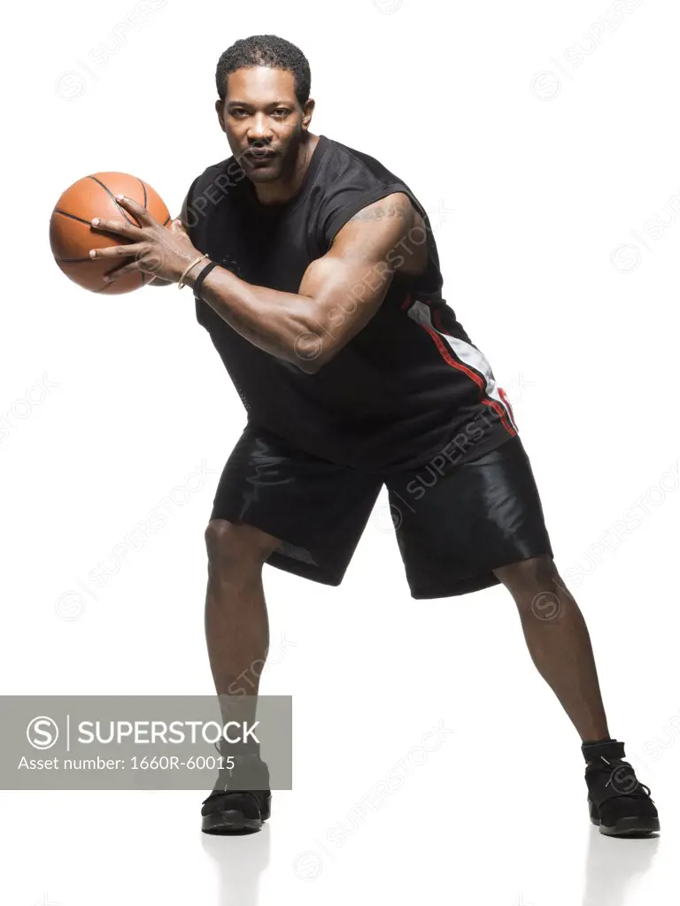 Mid adult man holding basketball in air, portrait