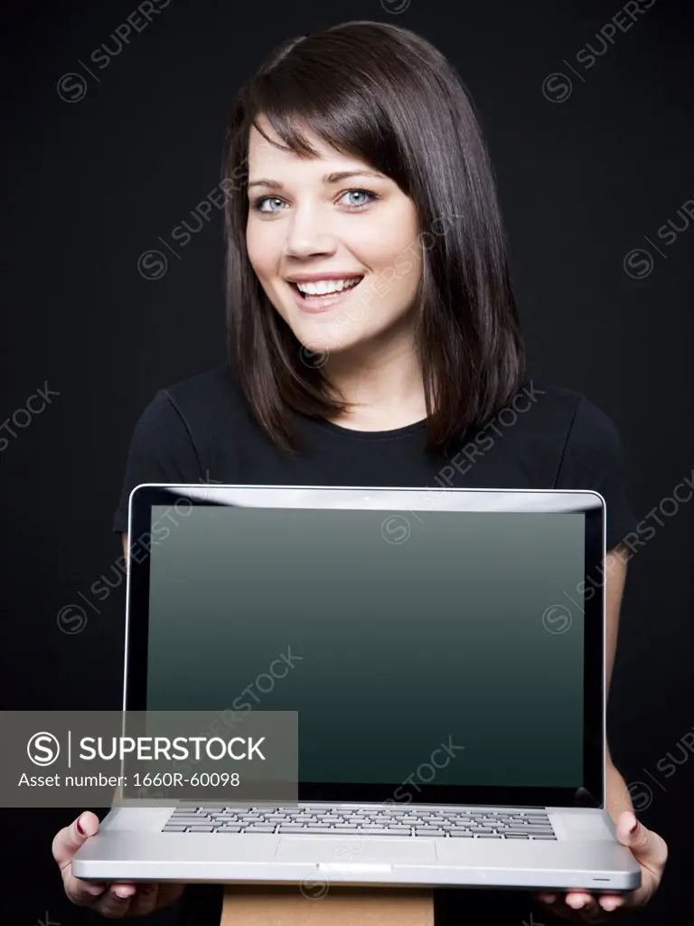 Young woman showing laptop, studio shot