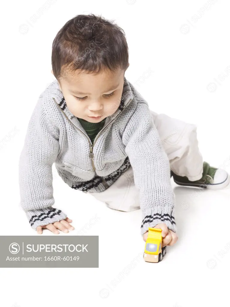 Studio shot of boy (18-23 months) playing with toy car