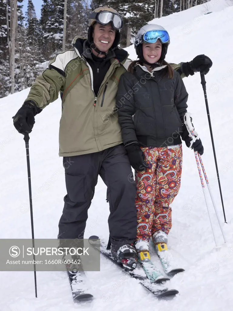 Portrait of father and daughter (12-13) skiing