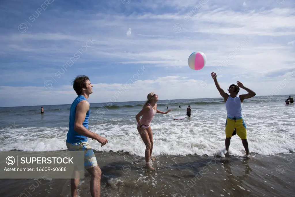 Three adults playing with a beach ball