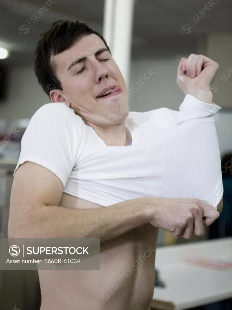 man putting on a shrunken t-shirt